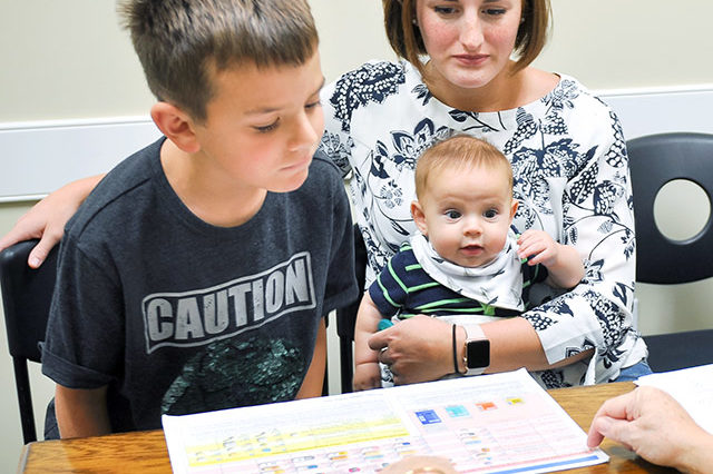 Mom with young ADHD son and baby learning about medications in Dr. Sheila Woods office at Greenville ADHD Specialists